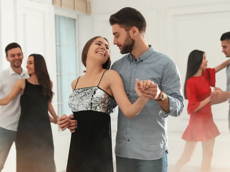Smiling couples dancing together in a bright studio dance class