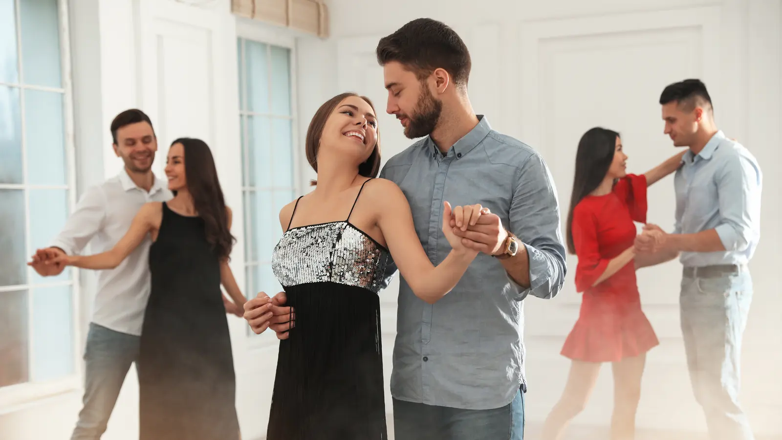 Smiling couples dancing together in a bright studio dance class