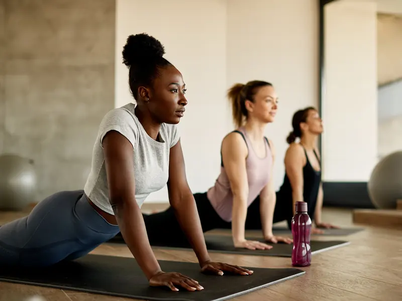 Women holding cobra pose on mats during a bright studio yoga class